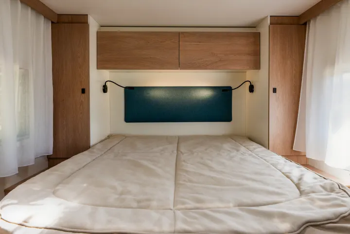 Modern rv rental bedroom with a comfortable bed, wooden cabinets, and soft lighting. Cozy interior for your travels.. JOA 75Q 2024