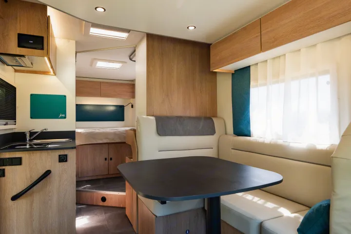 Bright, modern RV rental interior showing kitchen, dining, and sleeping areas. Perfect for your next road trip adventure.. JOA 75Q 2024