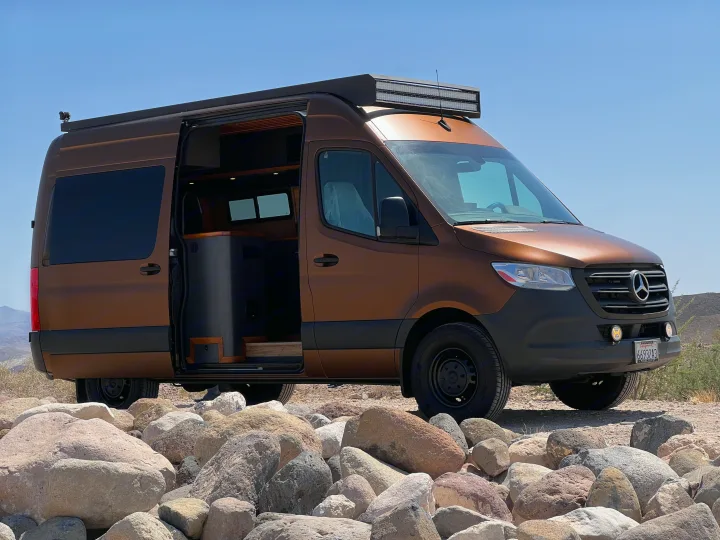 Stylish brown Mercedes-Benz Sprinter RV rental on rocky terrain under a clear sky, ready for adventure.. Mercedes-Benz Sprinter 2020