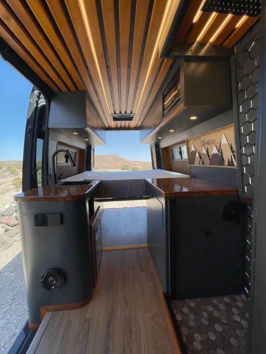 Explore this stylish custom camper van interior, available for rv rental, featuring a wooden ceiling & mountain views.. Mercedes-Benz Sprinter 2020