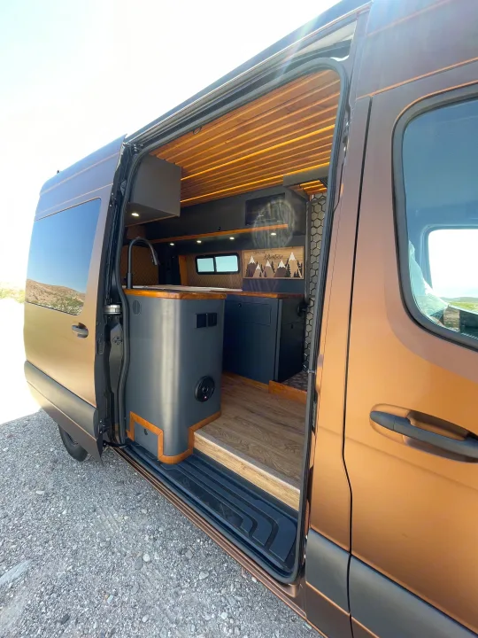 Spacious RV rental interior: custom camper van with modern kitchen, wood ceiling, & adventure art. Ready for van life!. Mercedes-Benz Sprinter 2020