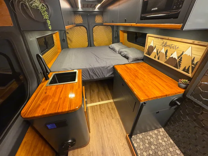 RV rental interior features a cozy bed, compact kitchen with sink, and shower. Modern design for adventure travel.. Mercedes-Benz Sprinter 2020