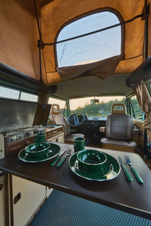 Classic pop-top camper van interior: dining table set, kitchen, & driver's cabin. Ideal for your next rv rental adventure.. Volkswagen T3 Westfalia 1986