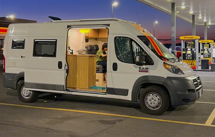This converted Ram ProMaster camper van, great for an RV rental, is at a Love's gas station at dusk. Person inside illuminated interior.. Ram promaster 2500 2017