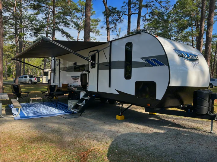 This spacious RV rental is fully set up at a serene campsite, complete with an extended awning & seating for outdoor leisure.. Forest River Salem FSX Platinum 2023