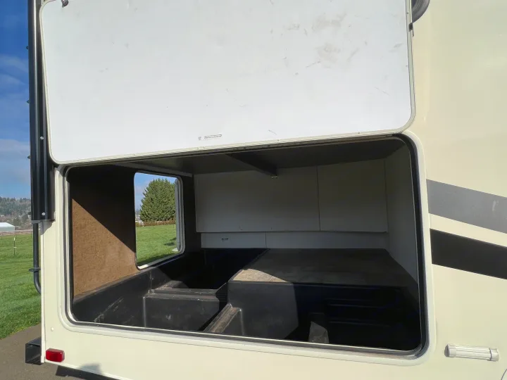 Open exterior storage in an RV rental, revealing a deep, molded compartment with a raised section.. Forest River Coachmen Freelander 2017