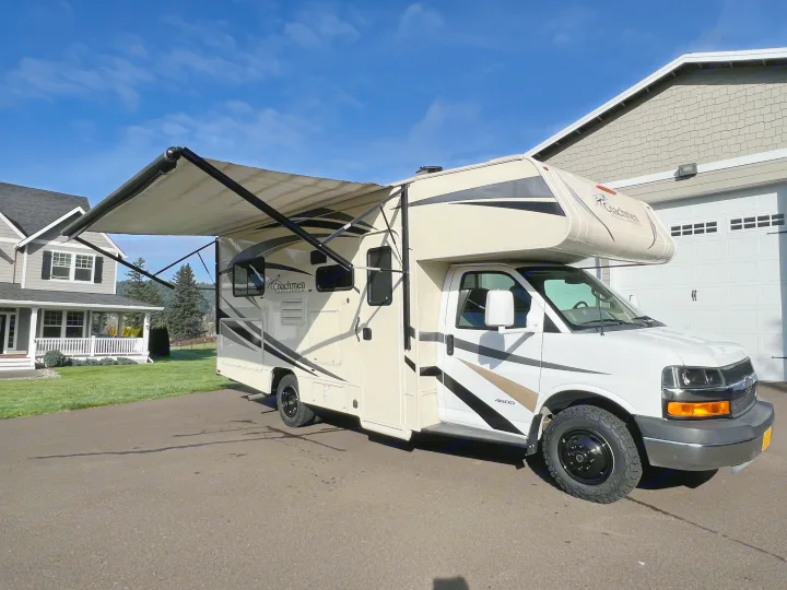 A Coachmen Freelander Class C RV rental with its awning extended is parked on a sunny driveway next to a house.. Forest River Coachmen Freelander 2017