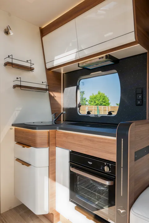 Modern RV rental galley featuring a compact oven, sink, and practical storage for adventures.. Pilote P696D ESSENTIEL 2024