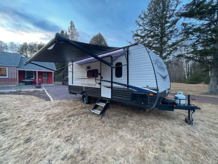 Springdale RV rental parked on a grassy lawn with its awning extended. Ready for outdoor travel adventures.. Keystone RV Springdale 2023