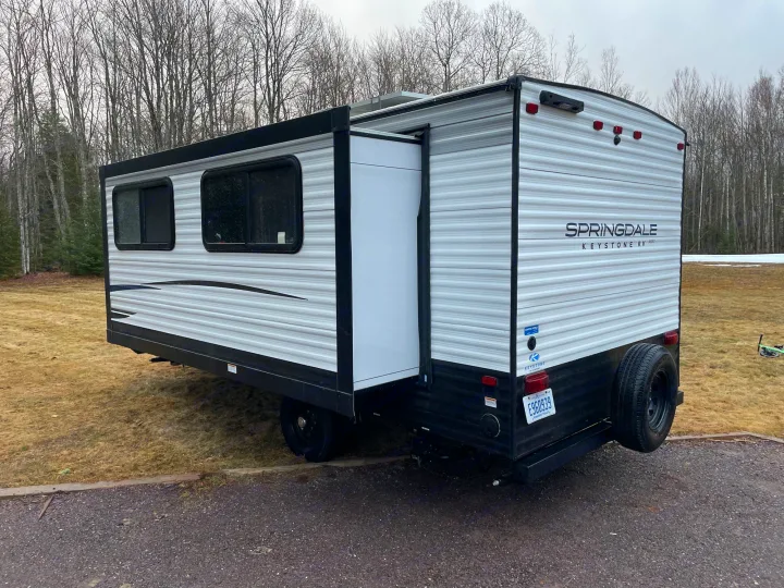 Keystone Springdale travel trailer with its side slide-out extended, offering more space. Ideal for an RV rental, parked outdoors.. Keystone RV Springdale 2023