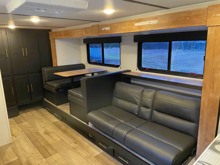 Modern RV rental interior features black dinette, sofa, sleek cabinets, and wood-look flooring. Ready for your adventure.. Keystone RV Springdale 2023