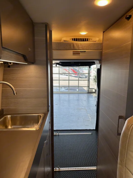 RV rental: Spacious camper van interior featuring a modern kitchen with sink, cozy bunk bed, and rear garage access.. Mercedes-Benz Entegra Launch 2024