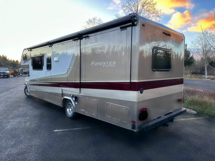 This tan and burgundy Forester motorhome, a spacious RV rental, is parked on asphalt, showing its side and rear.. Forester Forester Motorhome 2020