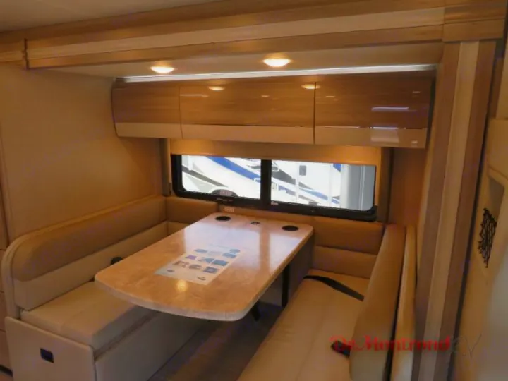 RV rental interior features a bright dinette with U-shaped booth seating, light table, and overhead storage.. Thor Tiburon 2023