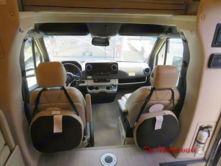 RV rental's clean cockpit with light-colored driver and passenger seats, items secured to backs. Ready for your road trip!. Thor Tiburon 2023