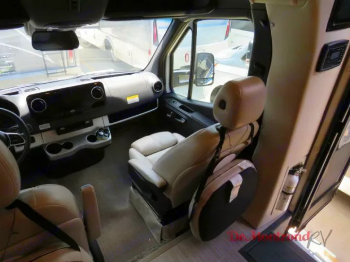 Modern RV rental cockpit: beige driver/passenger seats, detailed dashboard, and controls, ready for your next road trip.. Thor Tiburon 2023
