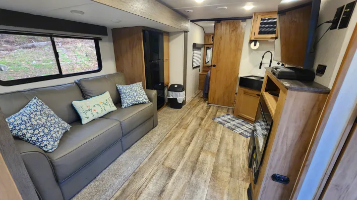 Spacious RV rental interior with a cozy couch, well-equipped kitchenette, and entertainment, ready for your travel adventures.. Forest River 22sw-l 2024