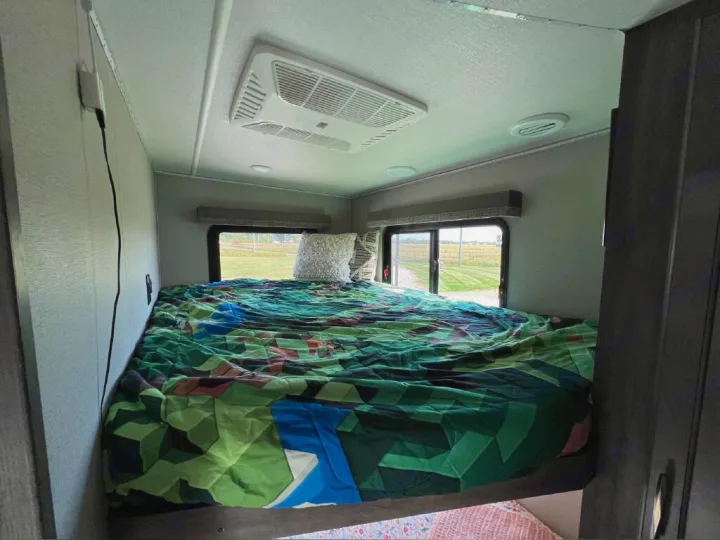 Cozy RV rental bedroom with colorful bedding, AC, and scenic window views.. Grand Design Solitude 2020