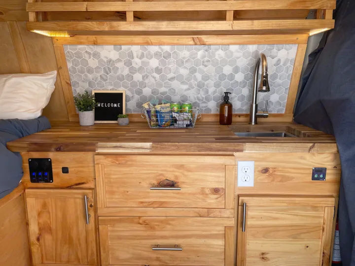RV rental kitchenette: custom wood cabinets, hexagon tile backsplash, sink, LED lighting. Functional space with outlets & controls.. Ford Ford E350 2011