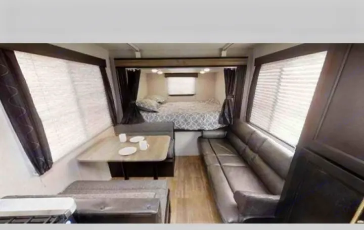 RV rental interior showcasing a comfortable bed, a practical dinette, and a long sofa for relaxing.. Forest River Cherokee Grey Wolf 2019