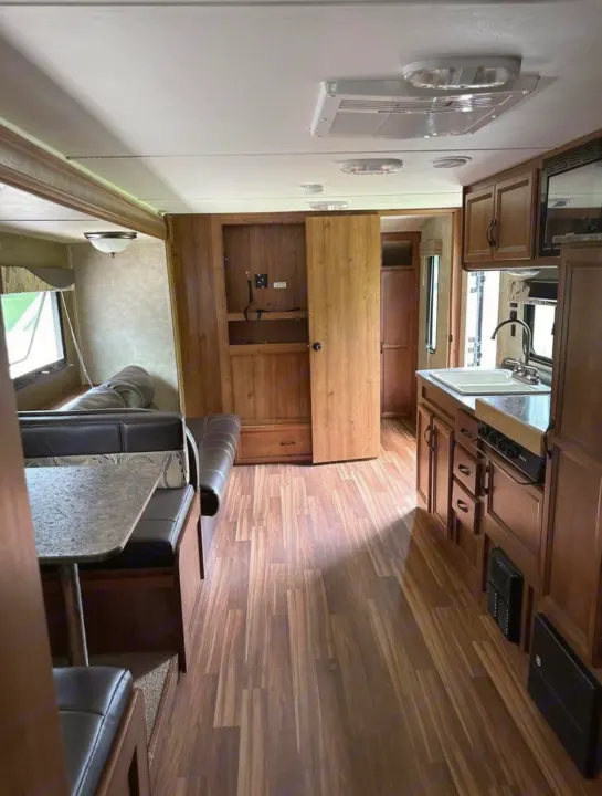 This RV rental offers a well-appointed interior with a kitchen, dining booth, and living area, featuring wood-look floors.. Gulf Stream Ameri-Lite 2016