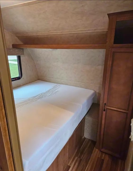 Comfortable RV rental bedroom featuring a white bed, overhead storage, and built-in wardrobe. Perfect for travel.. Gulf Stream Ameri-Lite 2016