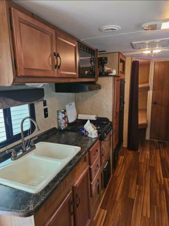 Explore this well-equipped RV rental kitchen featuring a sink, stove, microwave, and bunk beds. Ready for your travels!. Gulf Stream Ameri-Lite 2016