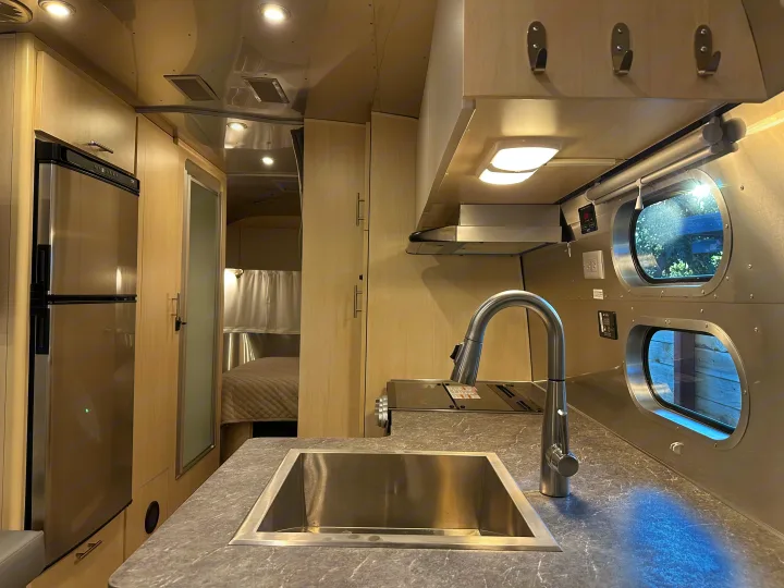 Modern RV rental interior featuring a sleek kitchen with stainless steel appliances and a comfortable bedroom area.. Airstream Flying Cloud 2023