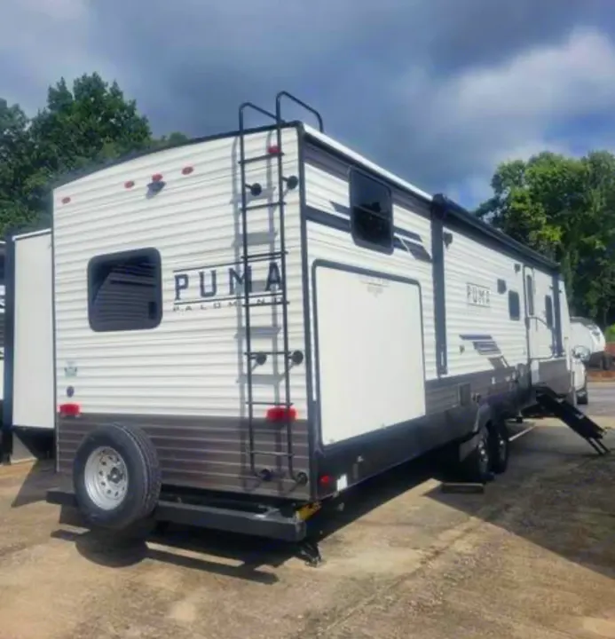 White Puma travel trailer RV rental, with a rear ladder, spare tire, and side awning, ready for adventure.. Forest River Palomino Puma 2022