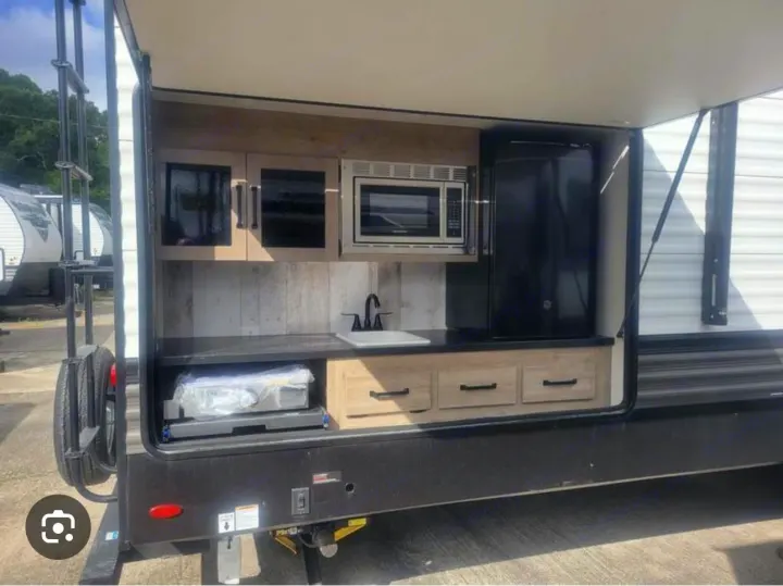 This RV rental features a convenient outdoor kitchen with a microwave, refrigerator, sink, cabinets, and a pull-out grill.. Forest River Palomino Puma 2022