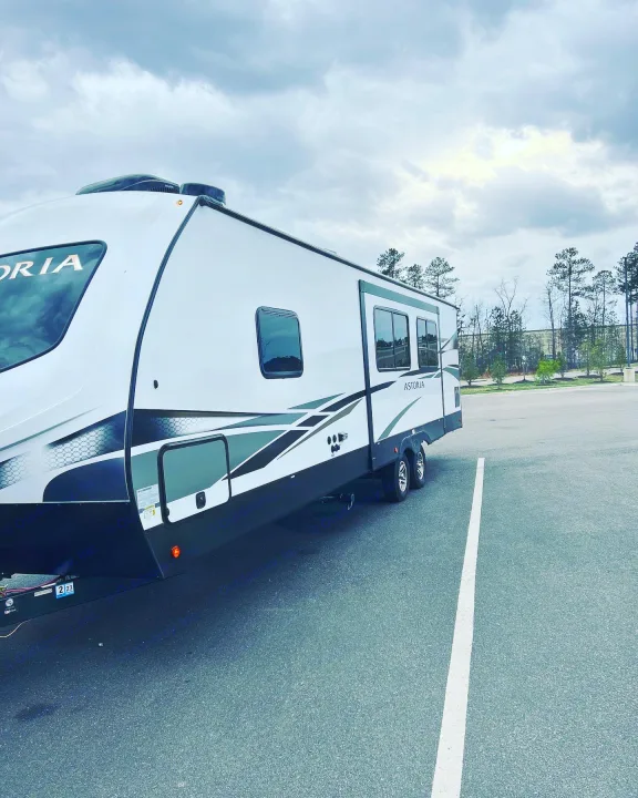 A sleek white Astoria RV rental, ready for travel, parked on asphalt with cloudy skies above.. Keystone RV Astoria 2903BH 2022