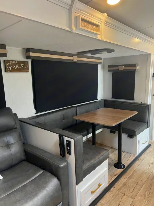 Spacious RV rental interior with a gray U-shaped dinette, wood table, and recliner, offering comfort and style.. Keystone RV Astoria 2903BH 2022
