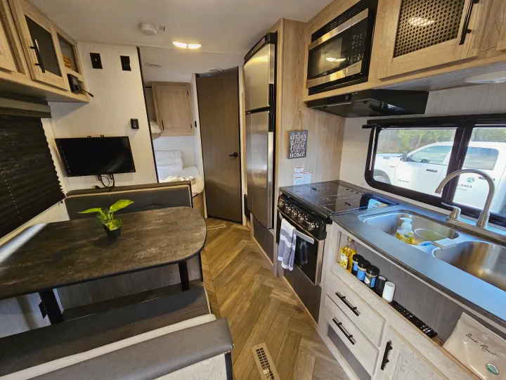 Clean RV rental interior featuring a kitchen, dining area, and cozy bedroom. Ideal for your next travel adventure.. Keystone Prowler 2021