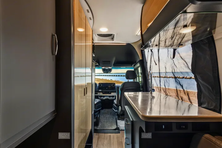 RV rental interior: galley, cab, and a scenic view of water and shore.. Thor Sanctuary 2023