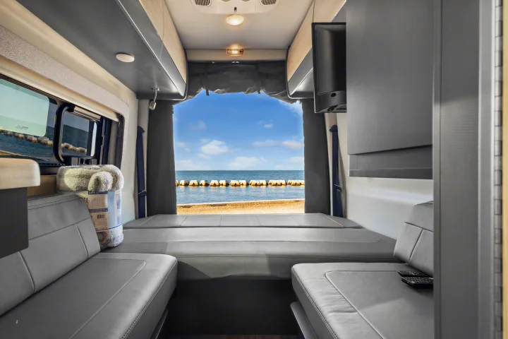 Cozy rv rental interior with plush grey beds and a stunning ocean view. Perfect for serene beachside adventures.. Thor Sanctuary 2023