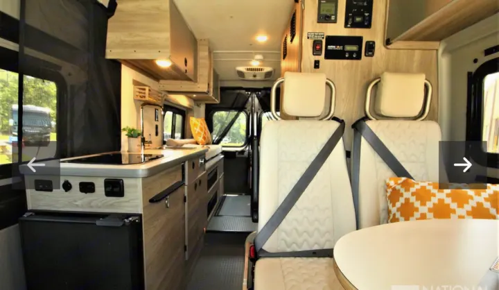 Compact rv rental camper van interior with kitchen, comfortable swivel seating, and control panels.. Winnebago Solis 2023