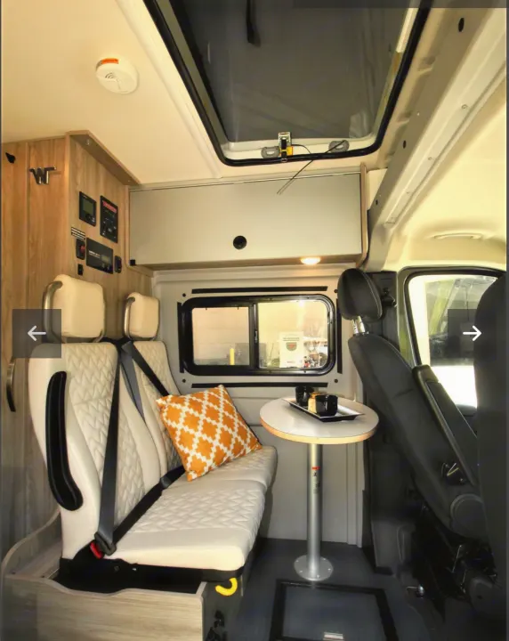 Inside an RV rental, showing a functional living space with comfy seating, a portable table, and integrated storage.. Winnebago Solis 2023