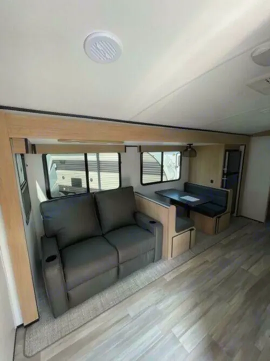 Spacious RV rental interior with a cozy sofa, dinette, and modern wood-look floor, perfect for your next road trip.. Cruiser Rv Corp Radiance 2022