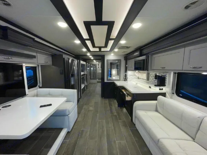 Spacious, modern RV rental interior in black, white, and gray, showcasing dining area, sofa, and kitchen.. Thor Motor Coach Venetian 2024