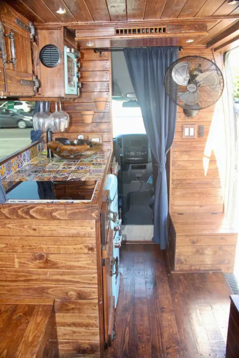 Inside an inviting RV rental, showcasing a rustic wood interior, a tiled kitchenette, and practical amenities for travel.. Mercedes-Benz Sprinter 2016