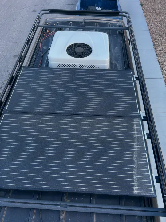 Overhead shot of an RV rental's roof, showing efficient solar panels, an AC unit, and a robust roof rack system.. Mercedes-Benz Sprinter 2016