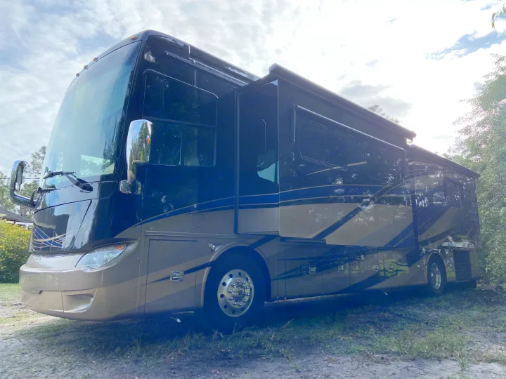 Ready for adventure! Rent this luxurious dark blue and tan RV rental with extended slide-outs, parked outdoors.. Tiffin Motorhomes Allegro Bus 2017