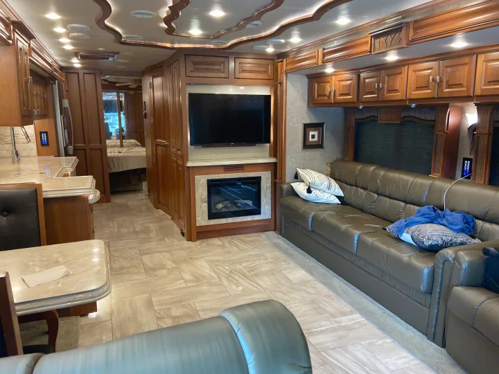 Explore this modern RV rental interior: comfortable living area with sofa, fireplace, TV; dining/kitchen space, and bedroom view.. Tiffin Motorhomes Allegro Bus 2017