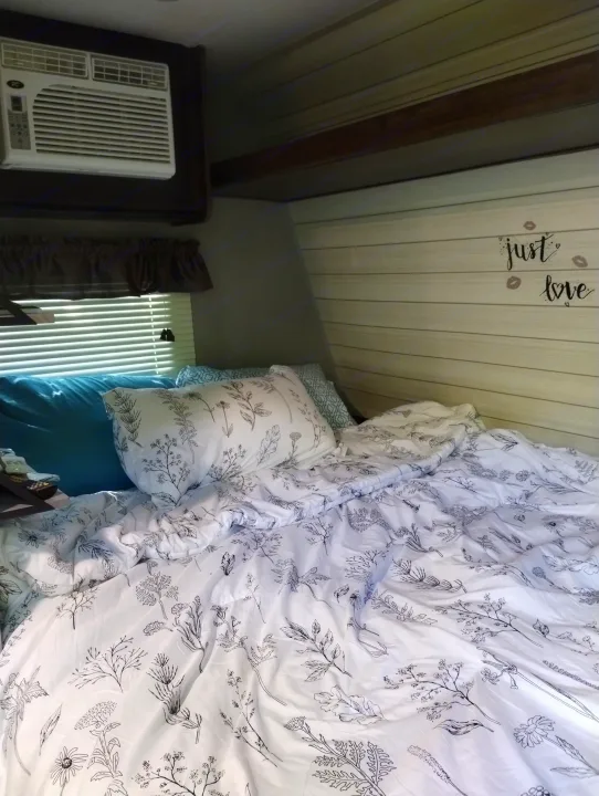 Inviting RV rental bedroom with floral bed, AC, and "just love" wall decal for a comfy stay.. Crossroads RV Z-1 Lite 2018