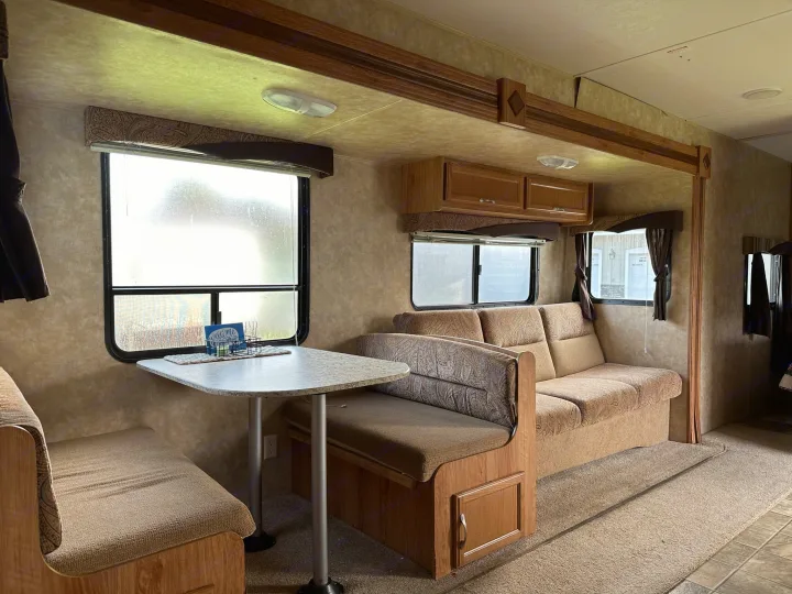 RV rental interior showing a dinette with bench seats, a sofa, and overhead cabinets in the living area.. Jayco Jay Flight 2009