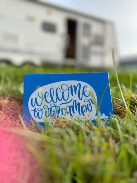 A blue "welcome to our camper" sign in the grass, inviting guests to a cozy rv rental at a sunny campsite.. Jayco Jay Flight 2009