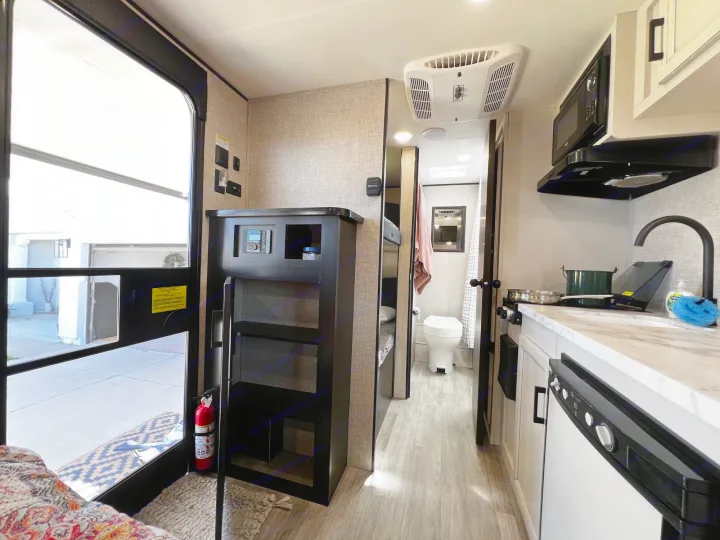Interior of an RV rental, featuring a compact kitchen, bathroom, and bunk beds. Bright and functional layout.. Jayco Jay Flight SLX Baja Edition 2023