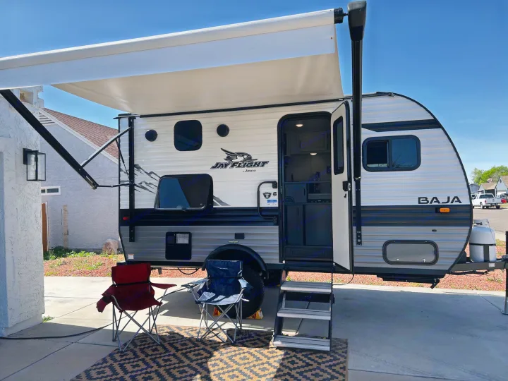 Jay Flight Baja RV rental setup with awning, chairs, and mat, parked for leisure.. Jayco Jay Flight SLX Baja Edition 2023