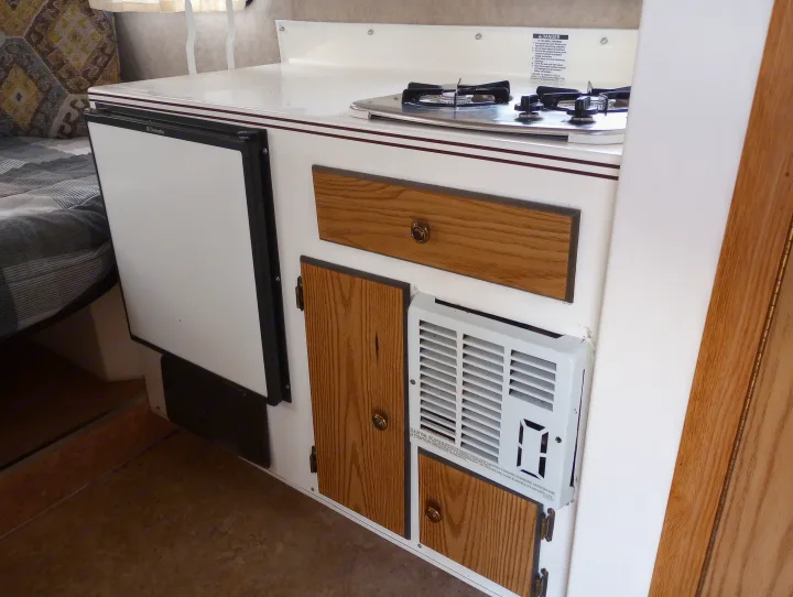 RV rental interior showcasing a compact kitchen with Dometic fridge, propane stove, and built-in heating/AC.. Scamp Scamp Trailer 2011