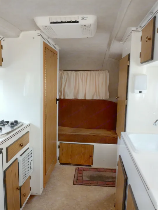 Compact rv rental interior: kitchen with stove and sink, a Coleman Mach AC unit, and cozy cushioned seating.. Scamp Scamp Trailer 2011